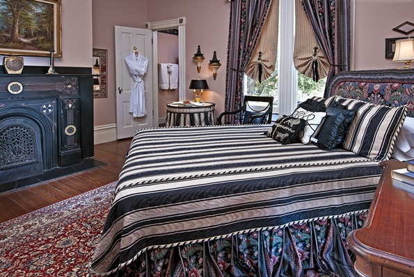 Bed in foreground with small table with Juice and berries on top on other side.  Bathroom in corner in background