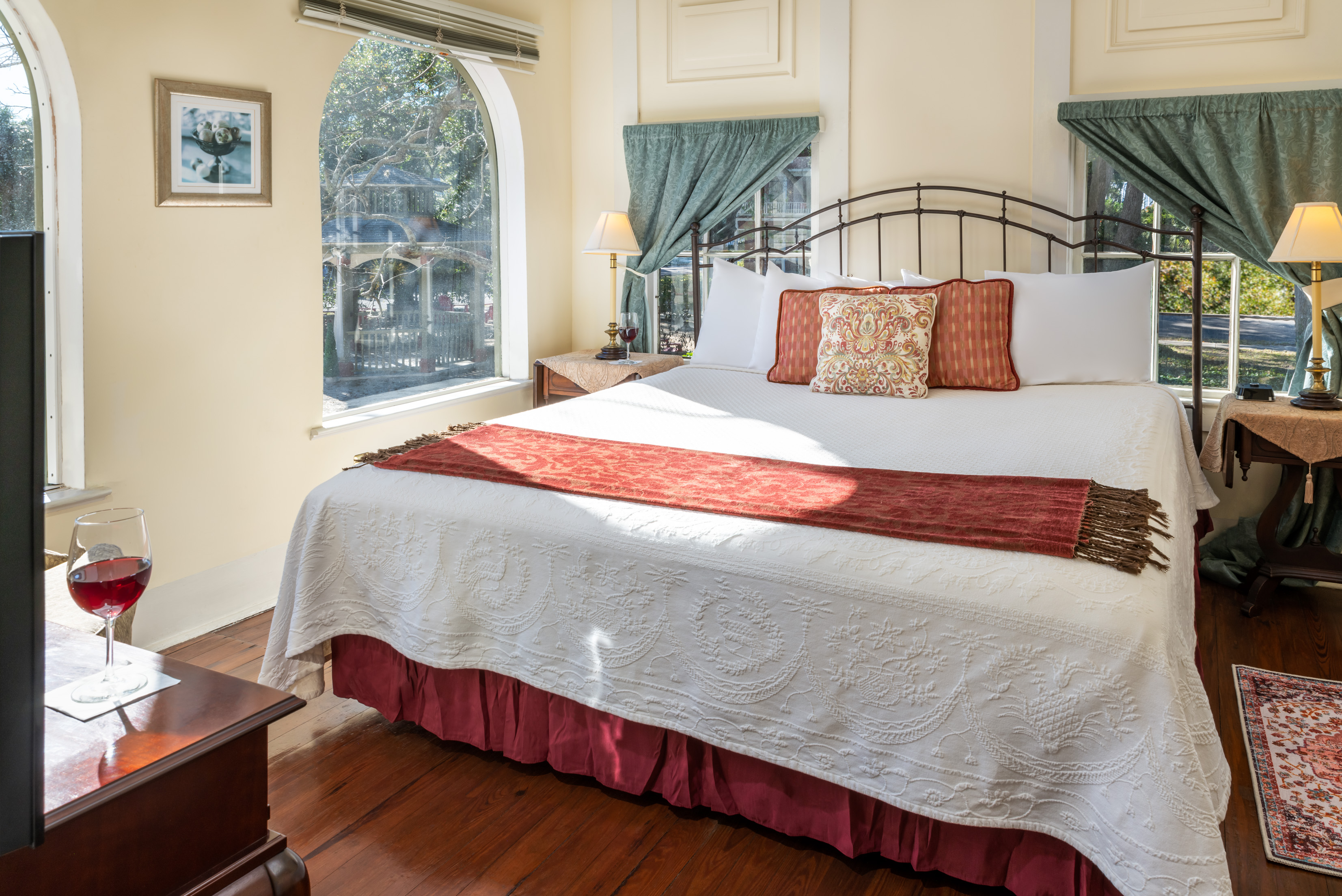Sunlit guest room with king bed and large arched windows