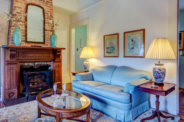 Living room with Blue sofa, coffee table and Fireplace.  Paintings on walls above sofa