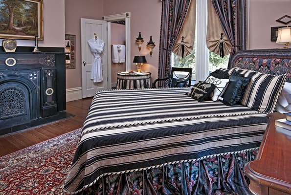 Bed in foreground with small table with Juice and berries on top on other side.  Bathroom in corner in background