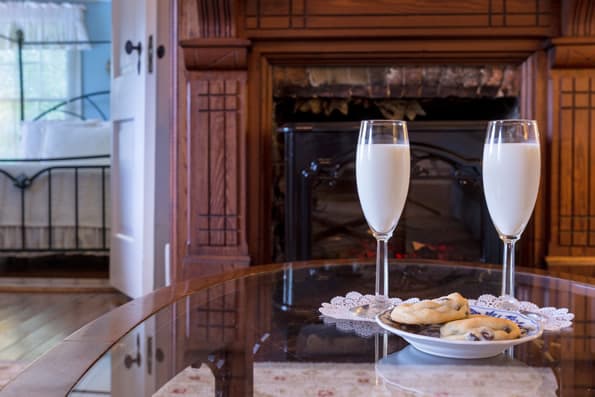 Plate of cookies with champagne flutes and champagne on table in front of wood mantled Fireplace