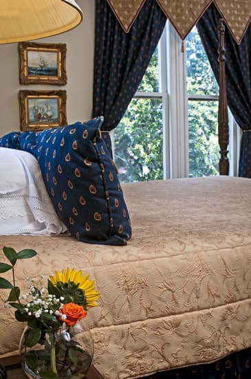 View from side of bed, with nightstand with flowers in foreground.