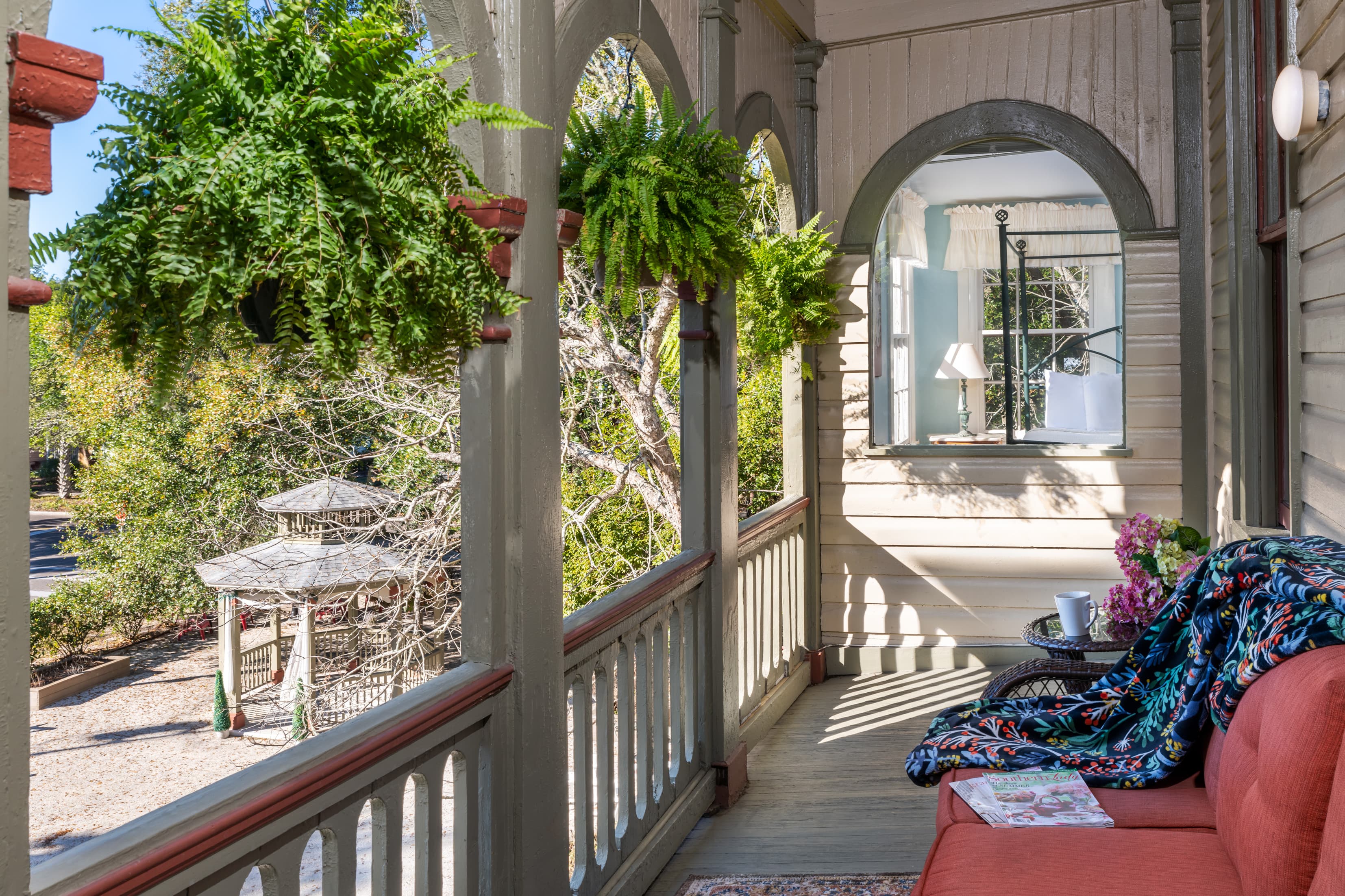 Charming wraparound porch with hanging ferns and cozy seating