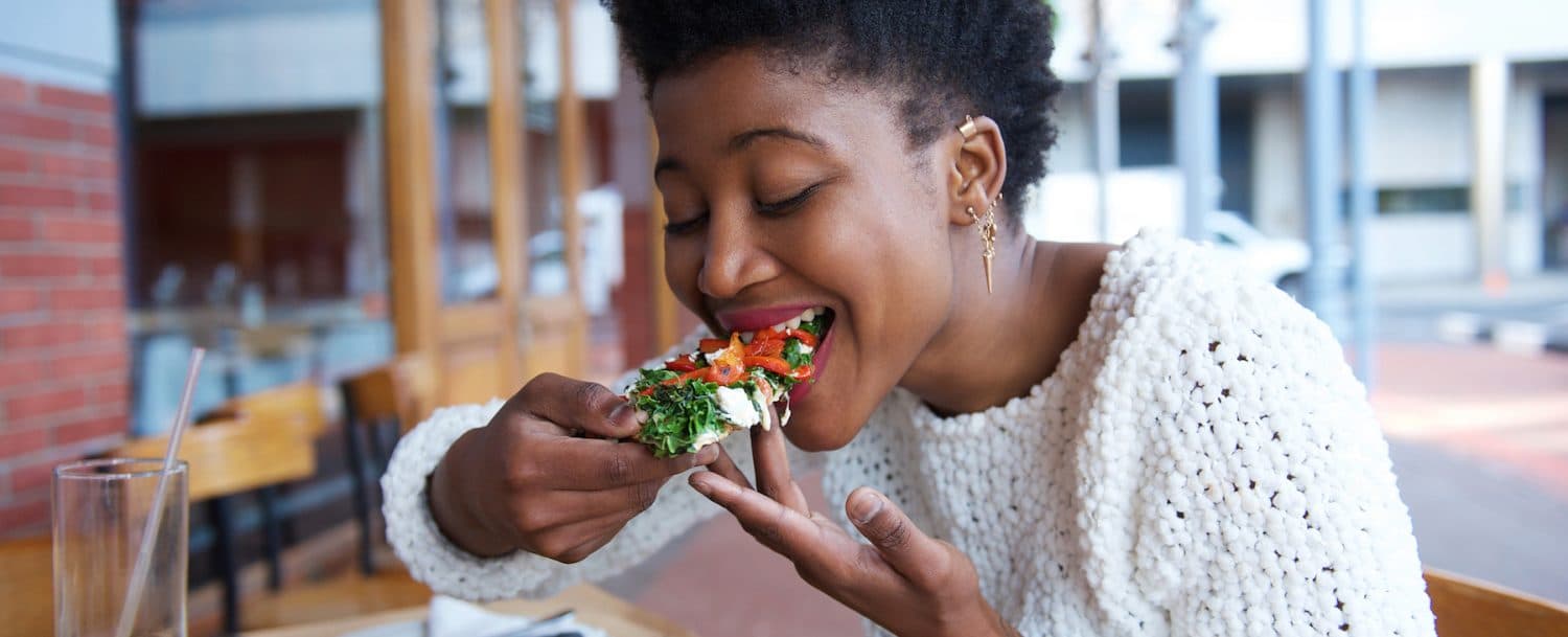 A woman enjoys a colorful salad while sitting at a cafe.