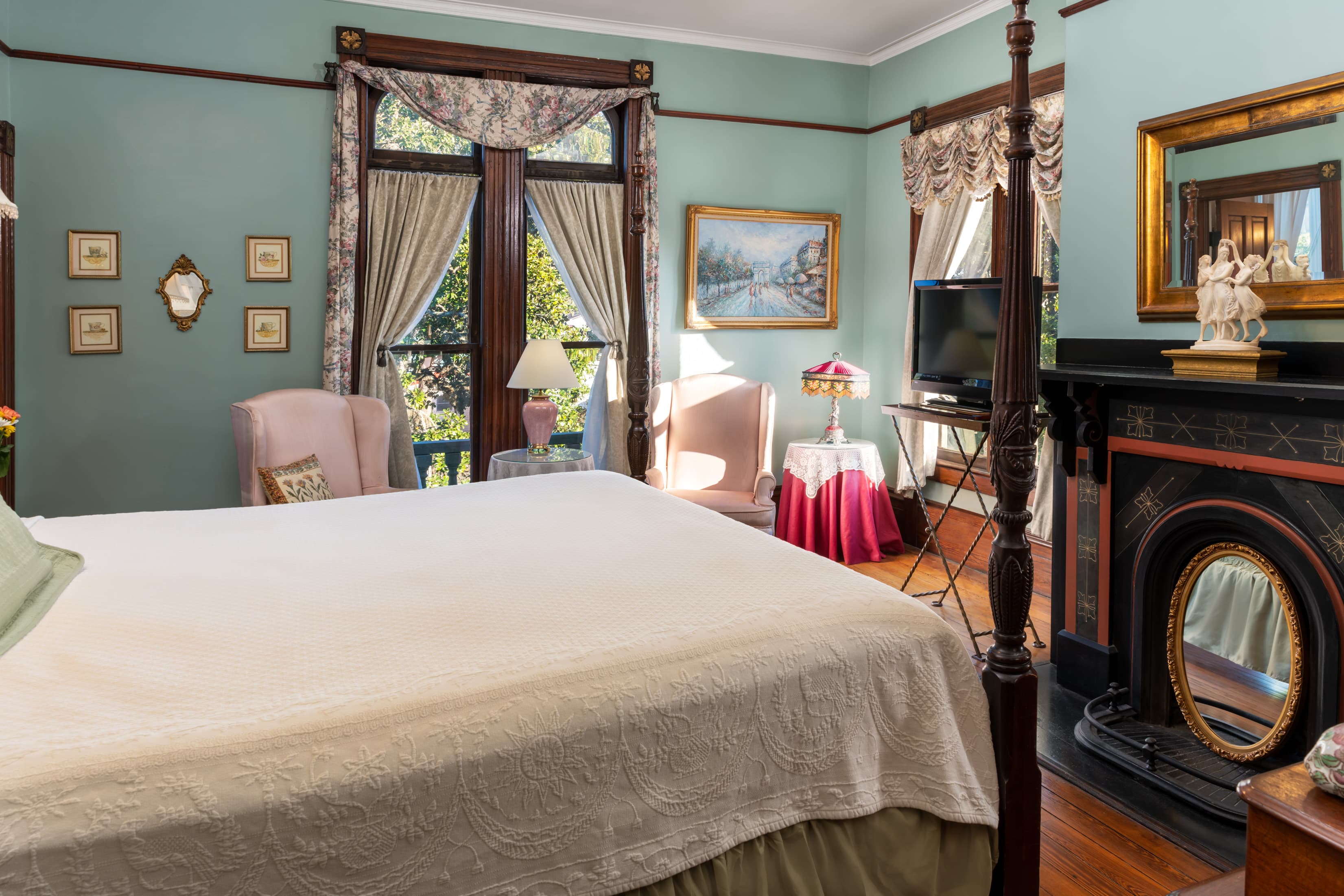 Bright historic guest suite with fireplace, large windows, and vintage décor