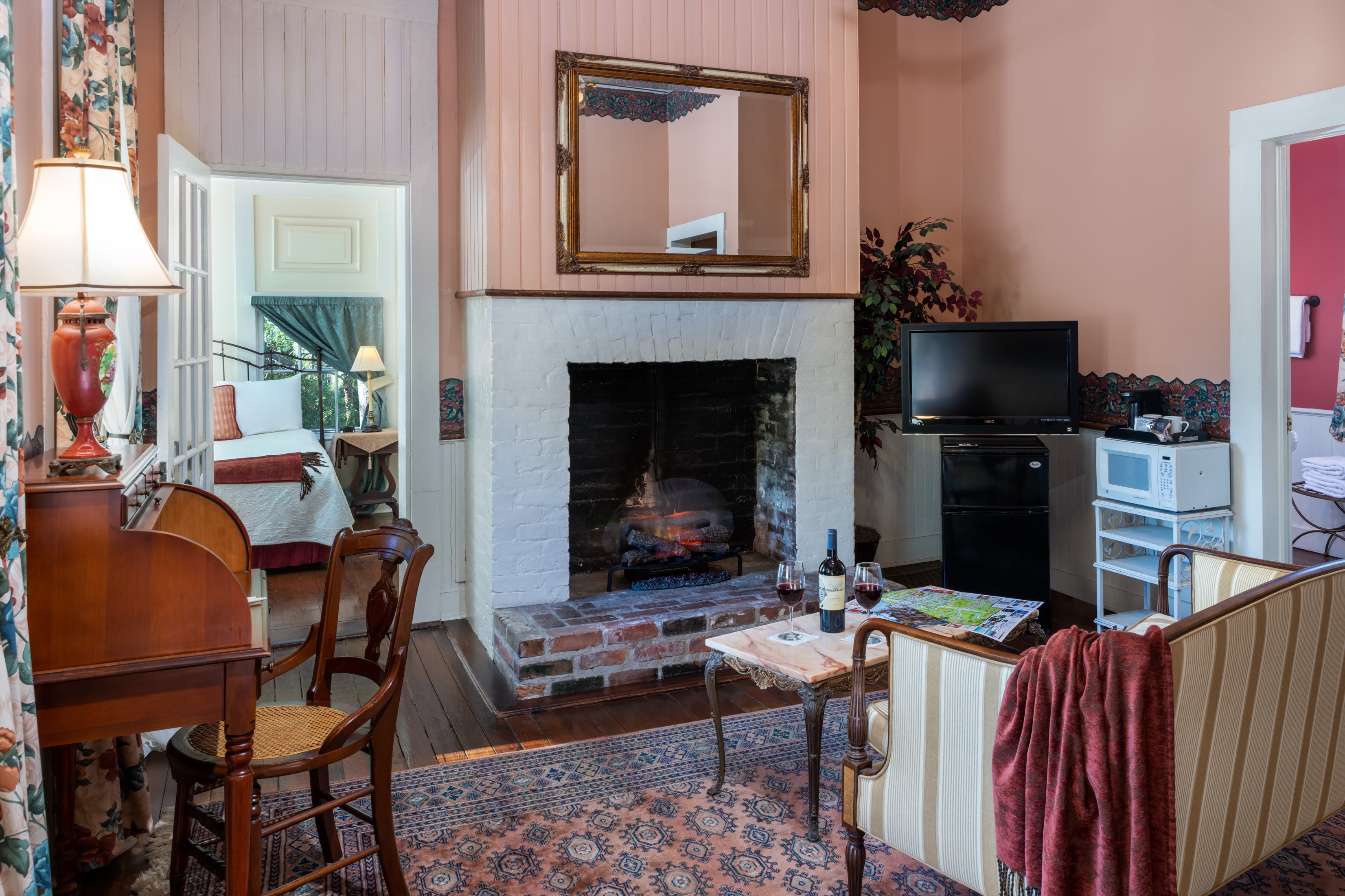 Cozy guest suite living area with fireplace, vintage furnishings, and hardwood floors