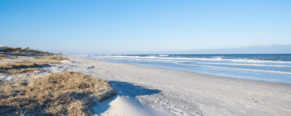 A serene beach scene with gentle waves and a clear blue sky.