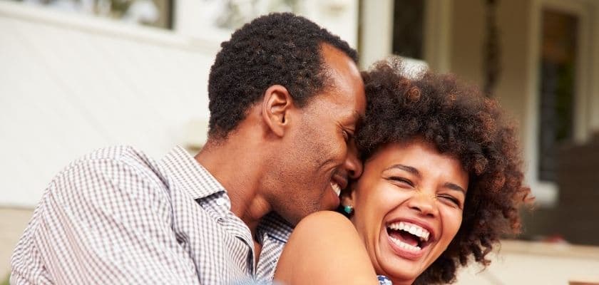 A couple shares a joyful moment, laughing together intimately.