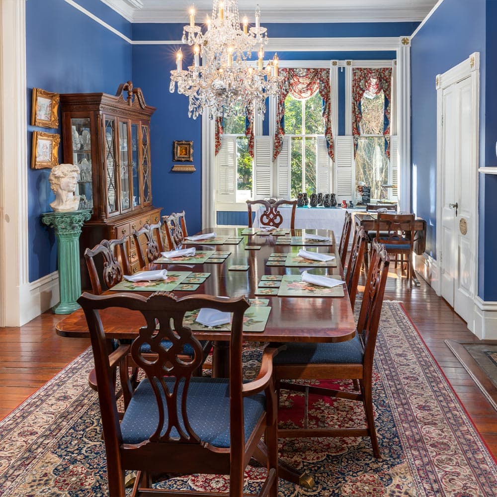 Elegant dining room with a long table, vintage decor, and blue walls.
