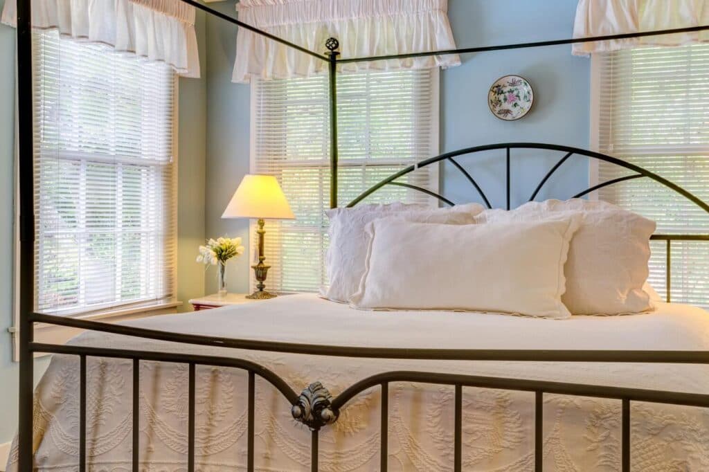 A cozy bedroom featuring a metal canopy bed, decorative pillows, and soft lighting from a bedside lamp.