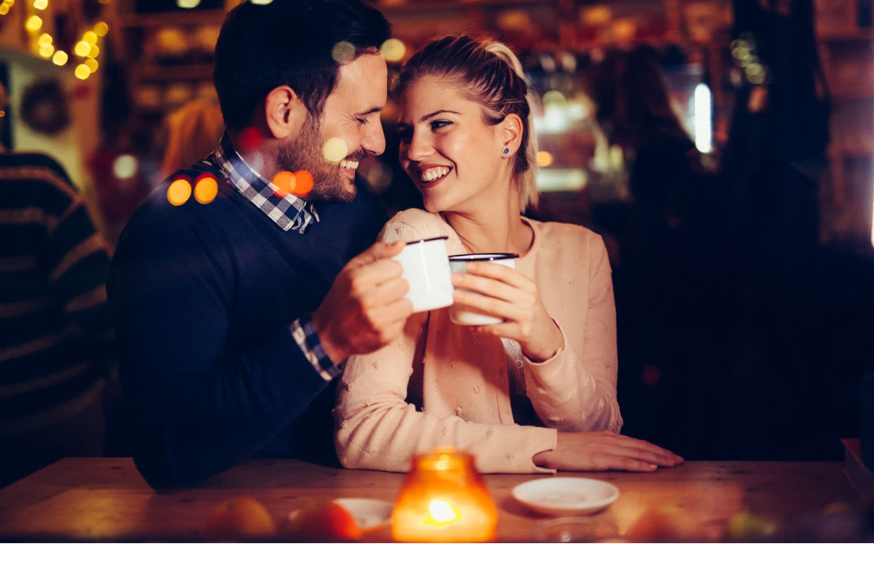A couple share a joyful moment while holding mugs at a cozy cafe. A couple share a joyful moment while holding mugs at a cozy cafe.
