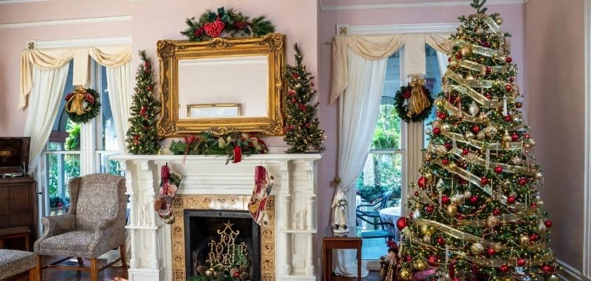A beautifully decorated living room featuring a large Christmas tree and a festive fireplace.