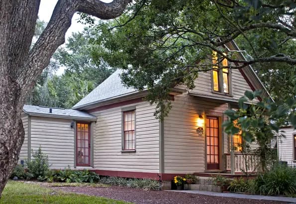 Outside entrance view has 3 stairs leading to vine covered overhanging entryway.