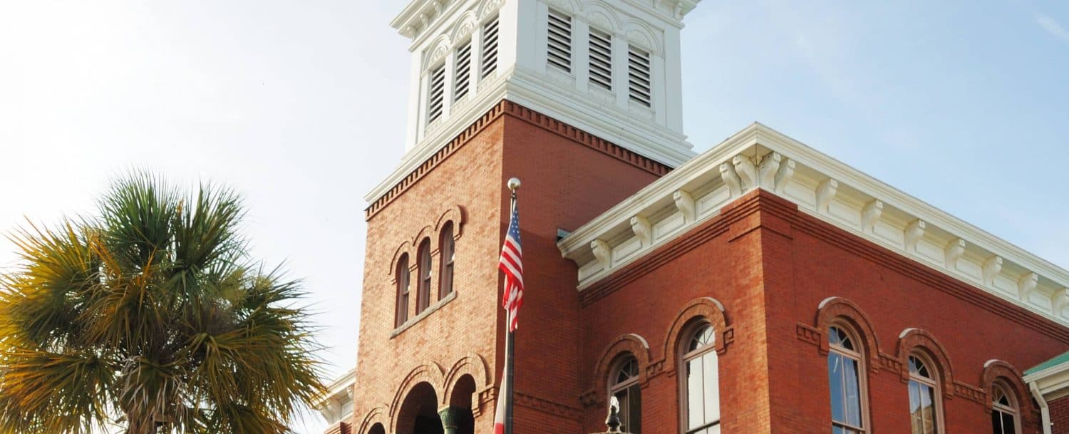 Historic brick building with a clock tower and American flag.