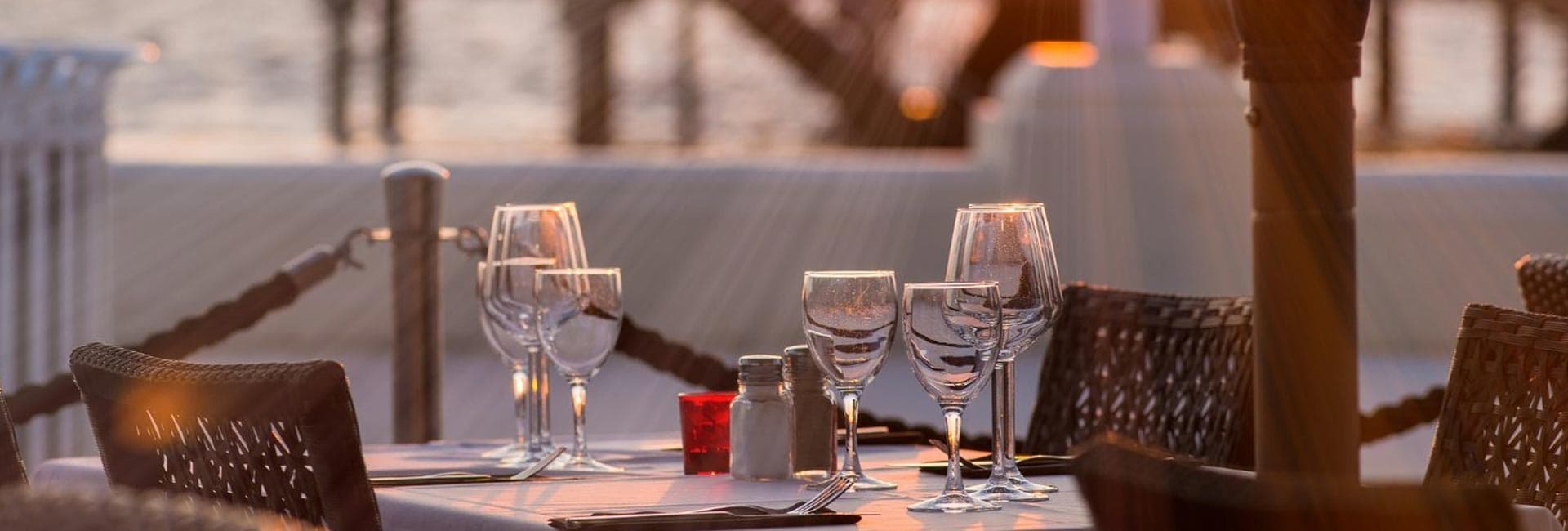 Table set for dinner with glasses and condiments, overlooking a water view.