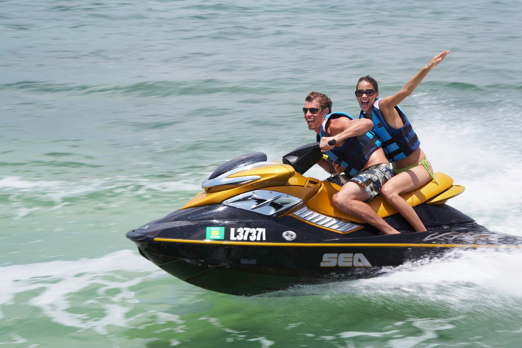 A man and woman in life vests joyfully ride a jet ski over the waves. A man and woman in life vests joyfully ride a jet ski over the waves.