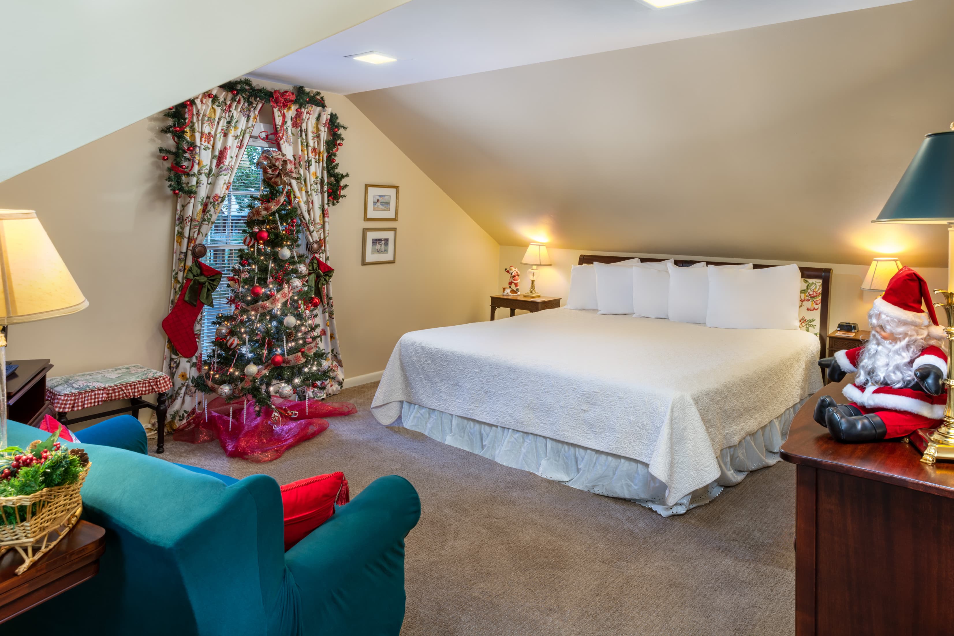 Festively decorated loft suite featuring a spacious king bed, cozy holiday décor, Christmas tree, plush seating, and warm seasonal charm.