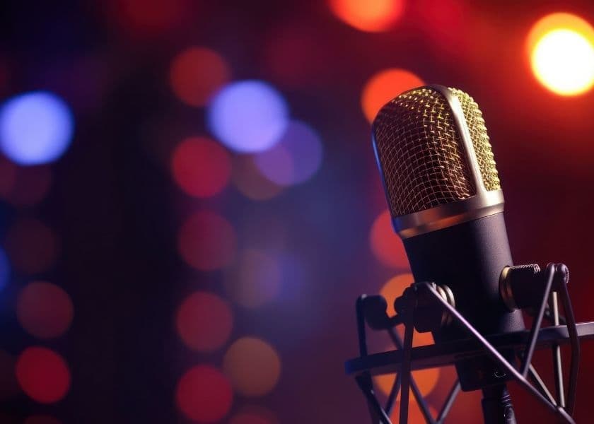 A close-up of a microphone against a blurred, colorful bokeh background.