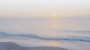 A serene sunrise over calm ocean waters.