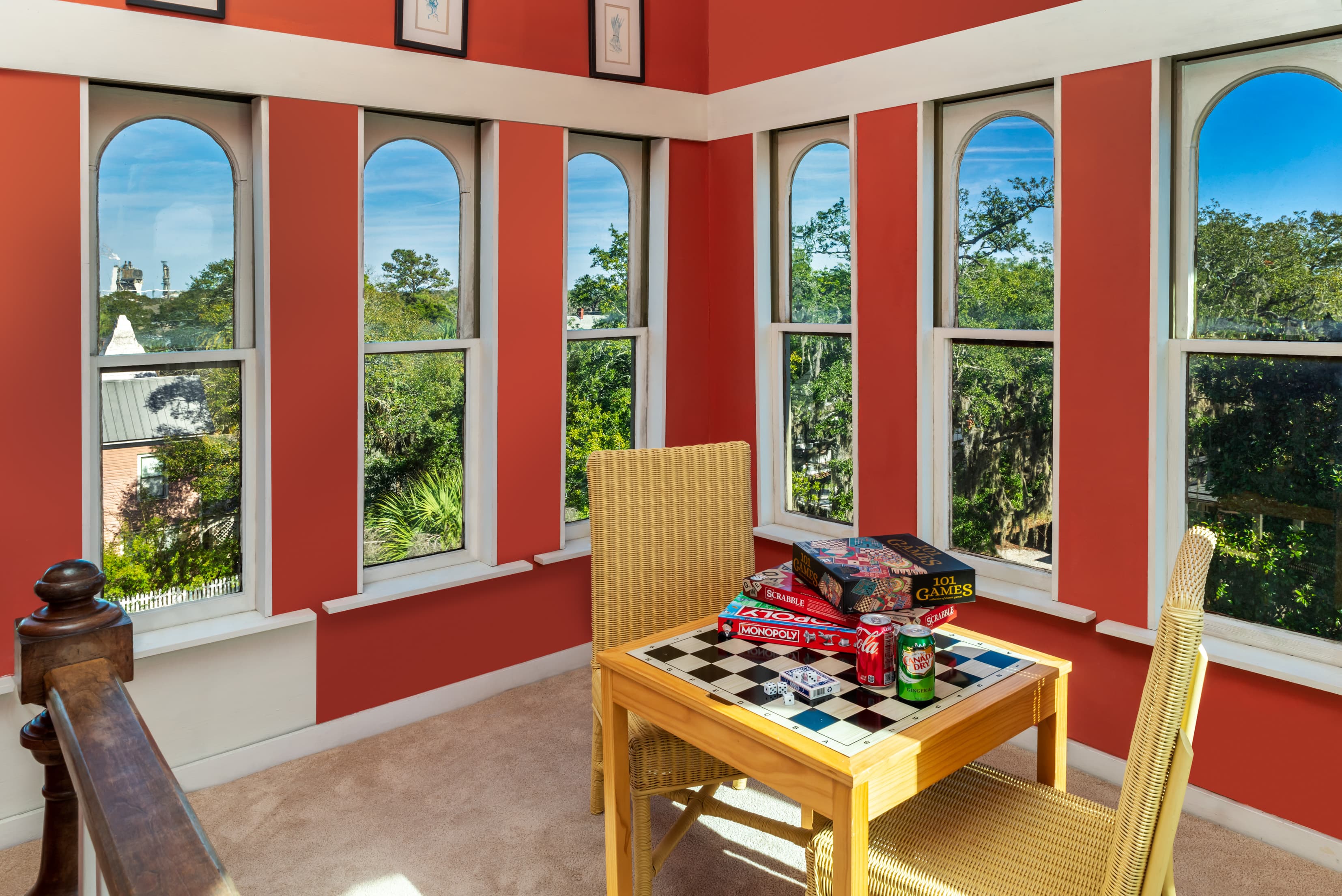 Bright tower room game nook featuring panoramic arched windows, treetop views, board games, and a sunny seating area perfect for relaxing.