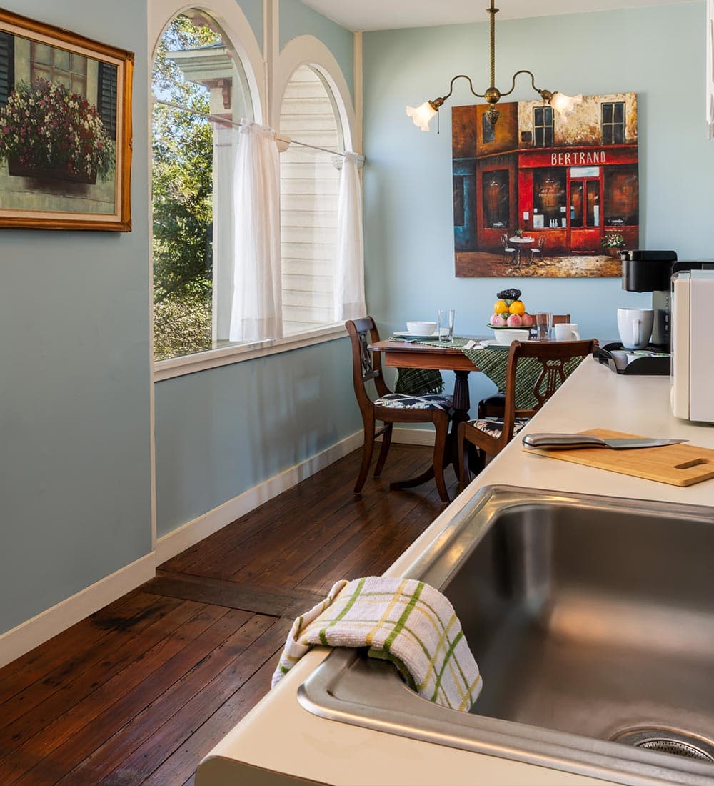 A cozy kitchen corner featuring a dining table, a window with sheer curtains, and decorative artwork.
