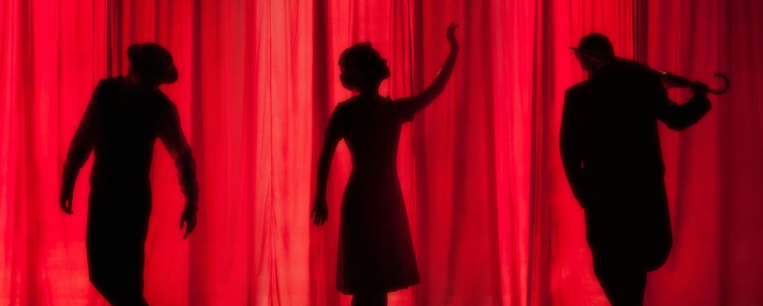 Silhouettes of three figures against a red curtain, evoking a theatrical atmosphere.