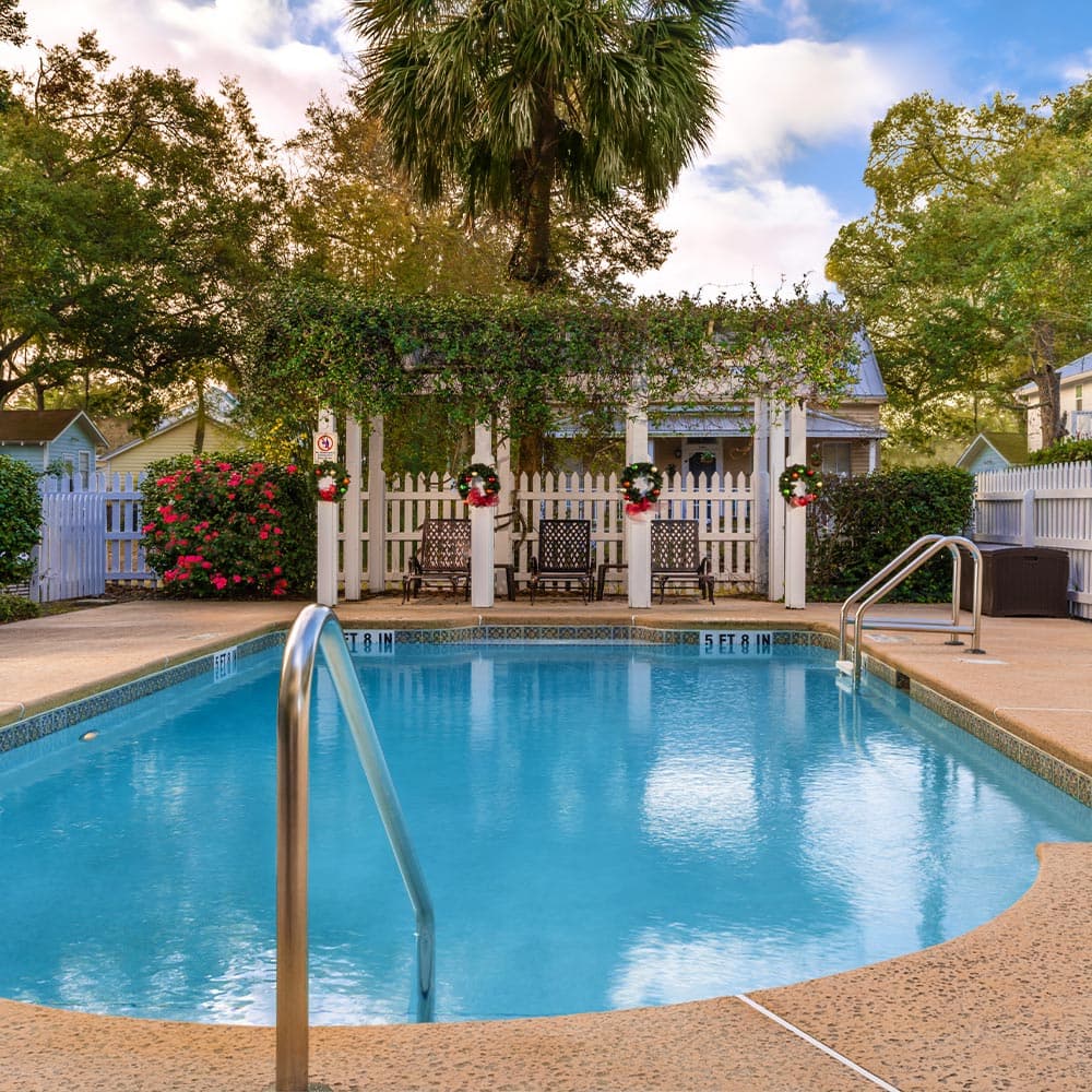 A serene swimming pool surrounded by lush greenery and a charming gazebo with festive decorations.