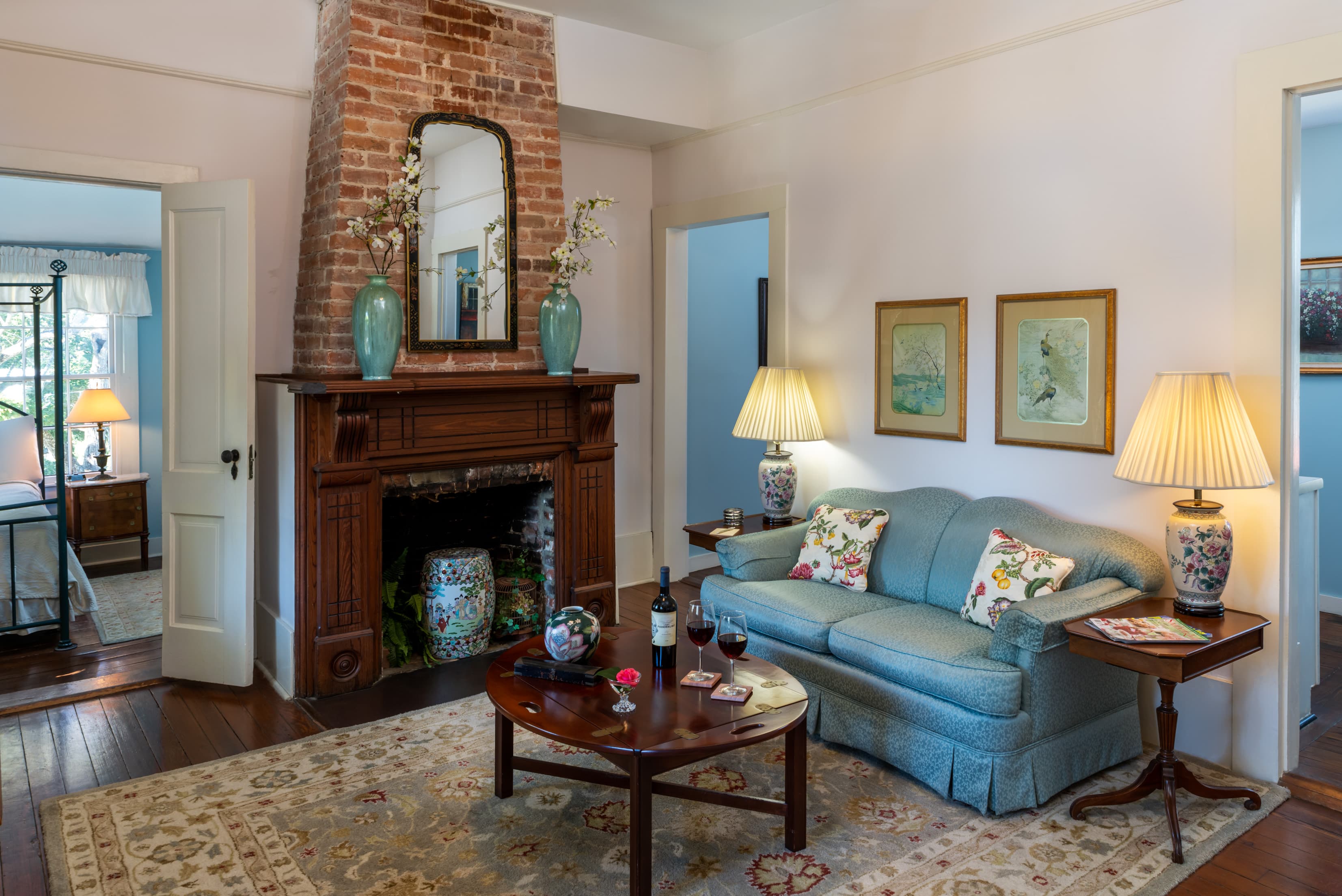 Elegant guest suite living area with fireplace, blue sofa, and vintage décor