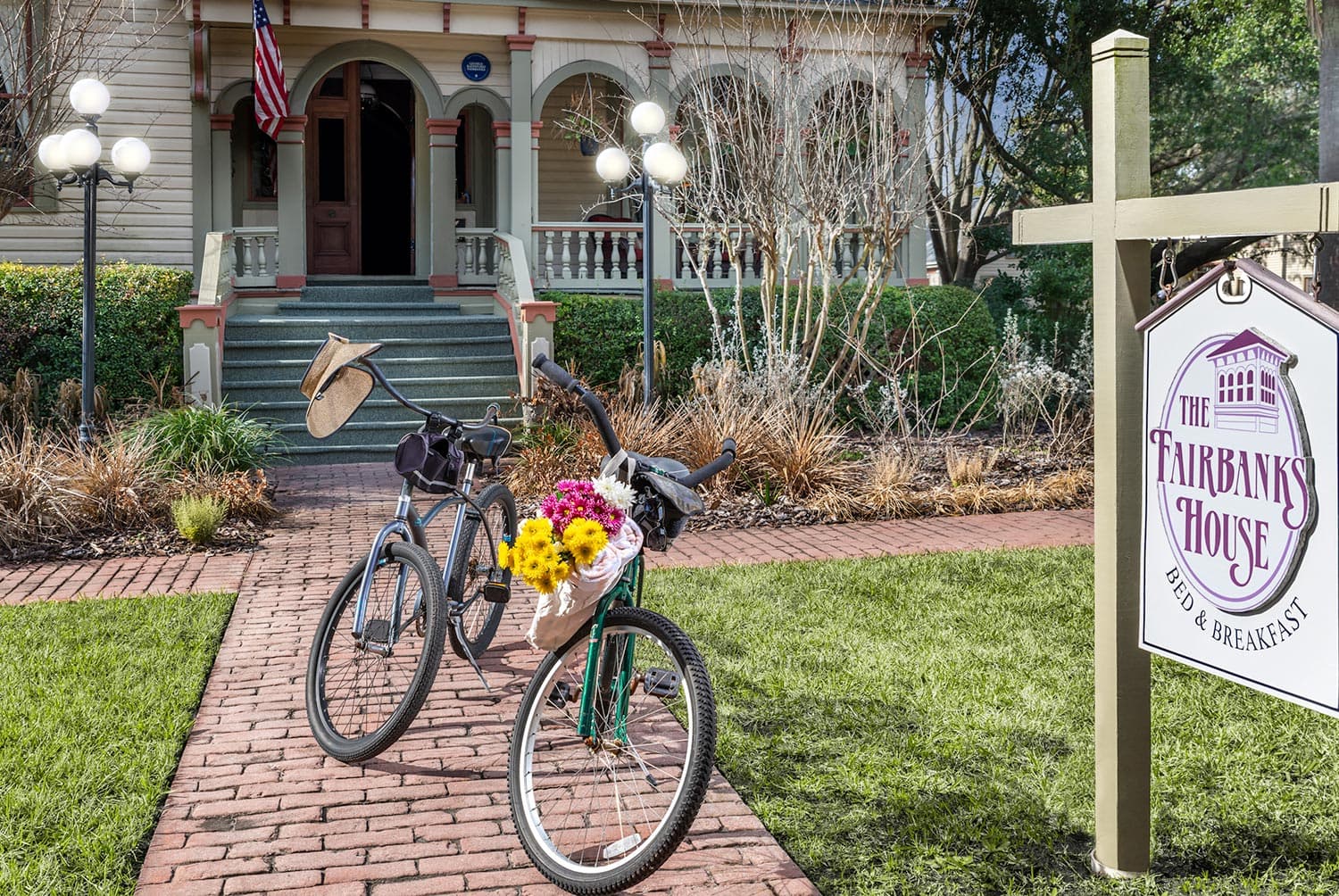 A pair of bicycles with flowers parked beside the Fairbanks House bed and breakfast, showcasing a welcoming entrance and greenery.