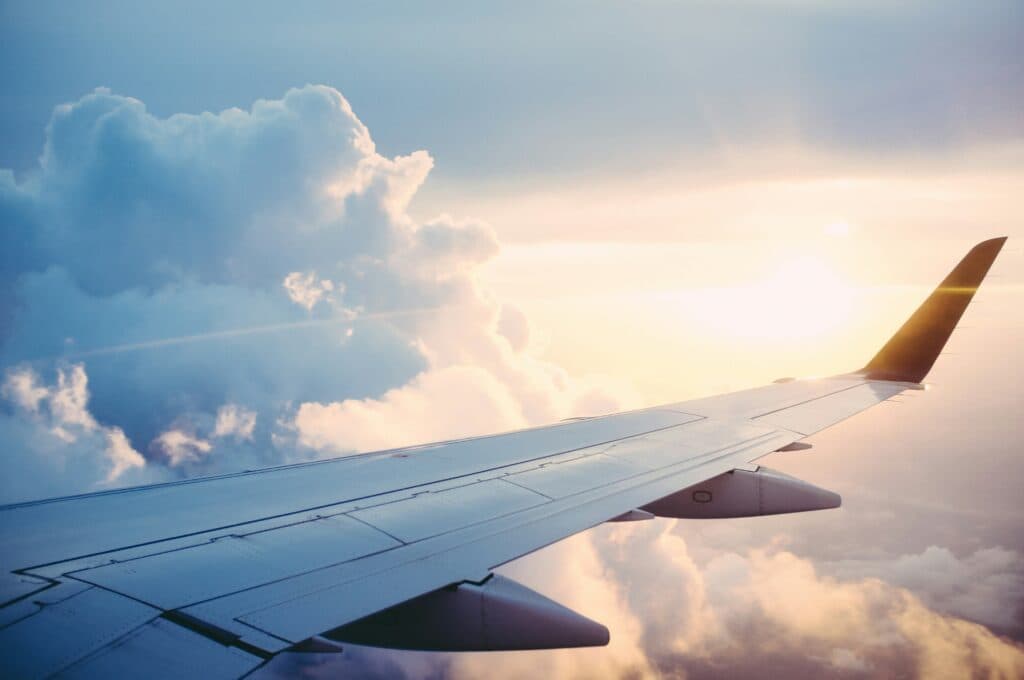 Airplane wing against a scenic sky at sunset with clouds.