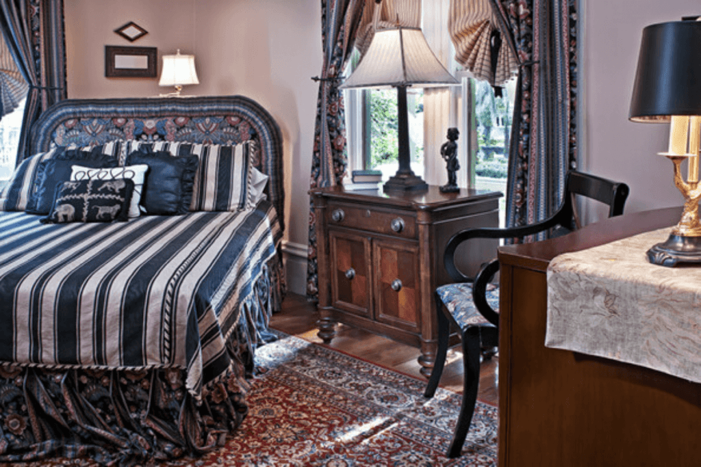 A cozy bedroom featuring a striped bedspread, decorative pillows, and antique wood furniture.