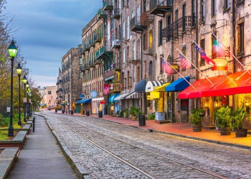 colorful street in georgia lined with brick buildings, flags, and green-lit streetlamps along a cobblestone path. colorful street in georgia lined with brick buildings, flags, and green-lit streetlamps along a cobblestone path.