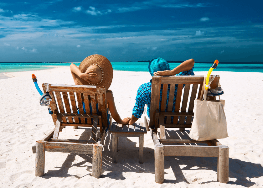 a couple holding hands and relaxing on lounge chairs on a sunny day at the beach a couple holding hands and relaxing on lounge chairs on a sunny day at the beach