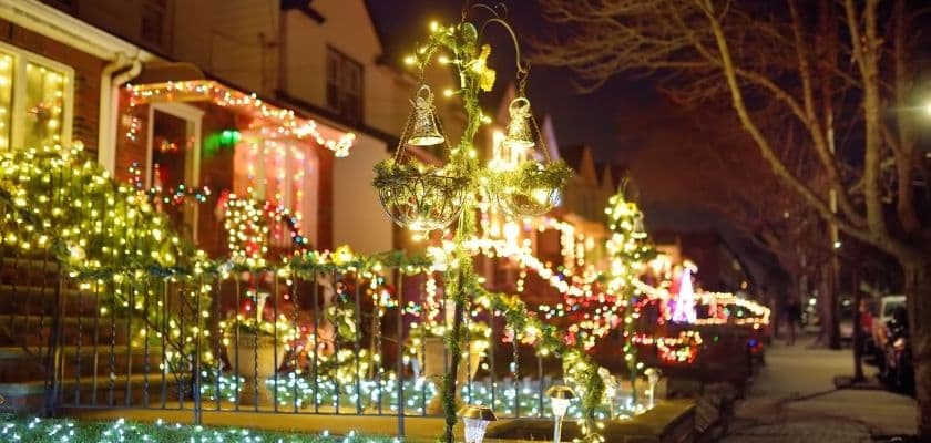 neighborhood street lined with houses decorated with colorful christmas lights at night